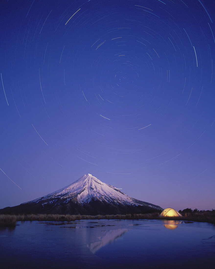 Star trails over Mt Taranaki and hikers tent Egmont National Park New Zealand