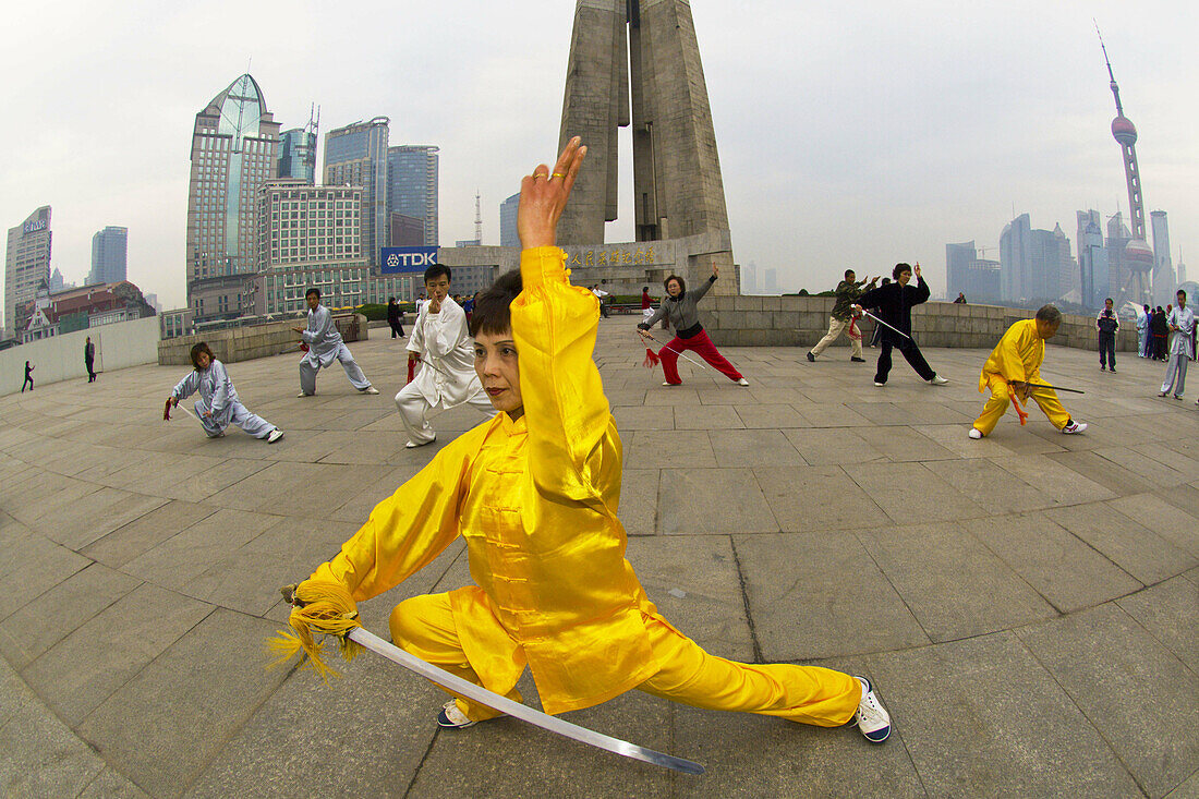 Chinese people practicing tai chi with swords in the early morning in Huangpu Park, Shanghai,  China
