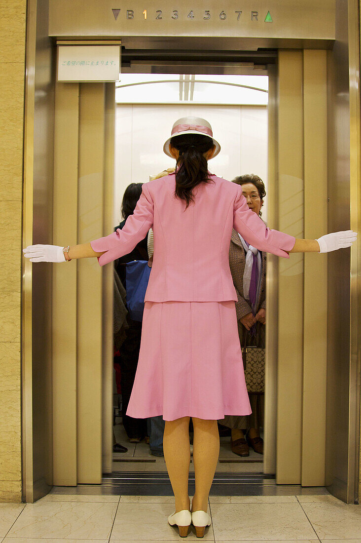 A Japanese department store elevator attendant making sure that as the doors close everyone is safe.