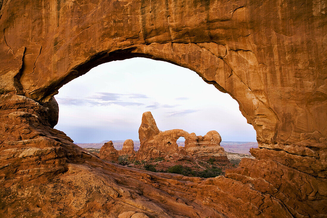 Pre-sunrise alpenglow paints North Window and Turret Arch in brilliant shades of red in Arches National Park,  Moab,  Utah