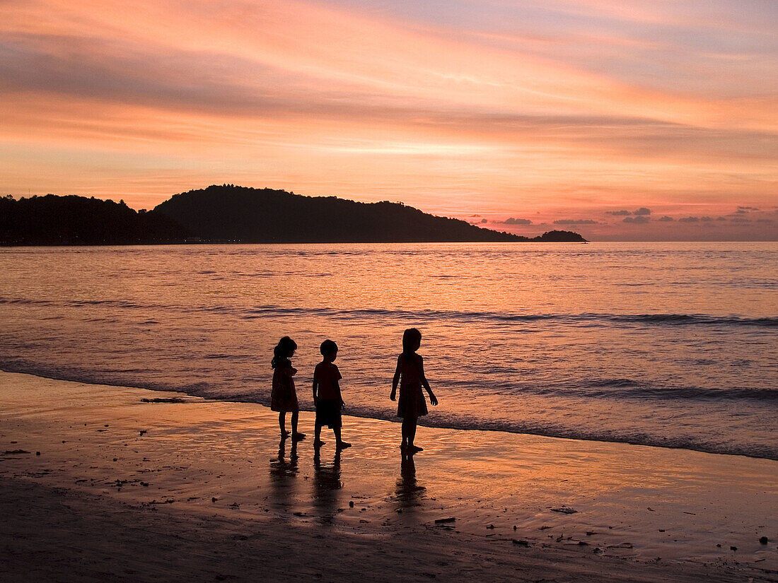 three children silhouetted on the beach at sunset in Phuket Thailand
