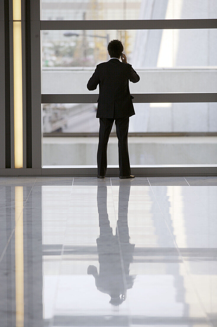 Silhouette of a Chinese man having a telephone conversation while standing in the lobby of an office building,  Hong Kong,  China,  Southeast Asia