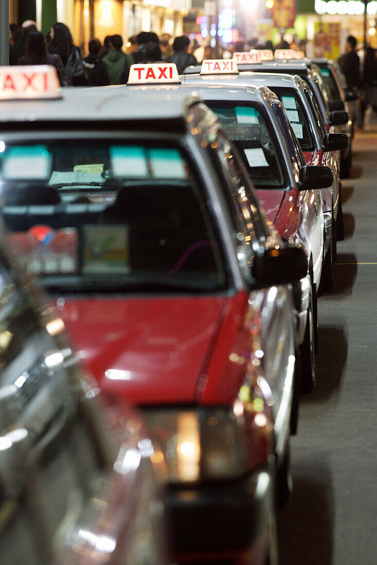 The typical red taxis queueing up idle at a taxi stand in Wanchai (Wan Chai) in the night,  Hong Kong Island,  Hong Kong,  China,  Southeast Asia