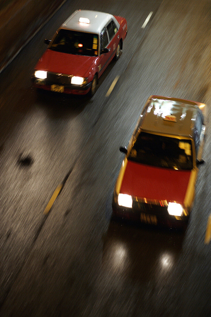 Two red blurred taxis behind each other moving in high speed on the street  in Wanchai (Wan Chai),  Hong Kong,  China,  Southeast Asia