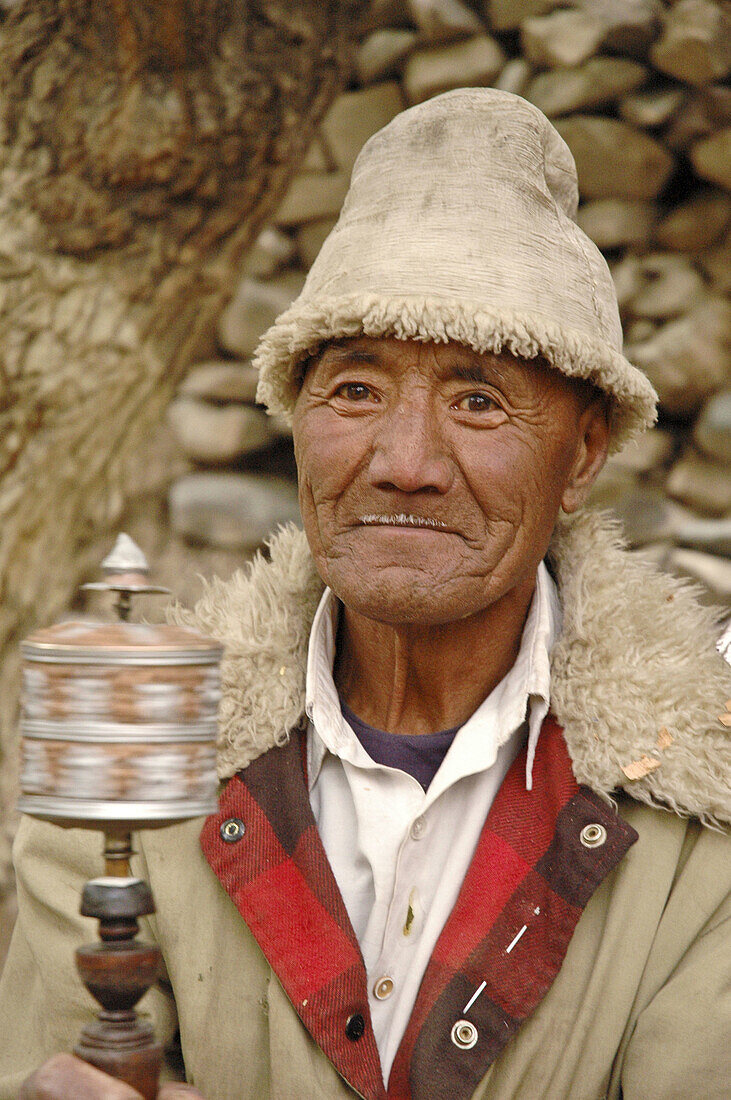 A happy tibetan man spinning a prayer wheel Alchi,  Ladakh,  India