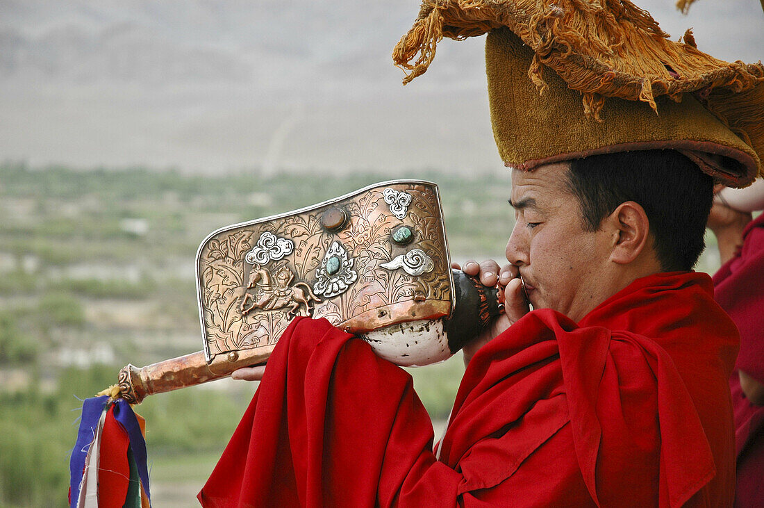Monk blowing a conch shell for the moring call to prayer Tiksey,  Ladakh,  India