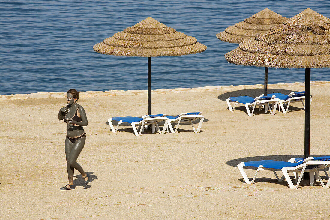 Jordan,  Dead Sea Woman at Marriot Hotel beach with dead sea mud on her body