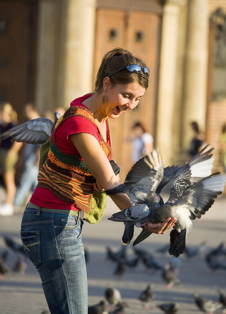 Poland,  Krakow,  Main Market Square,  pigeons and young woman having fun