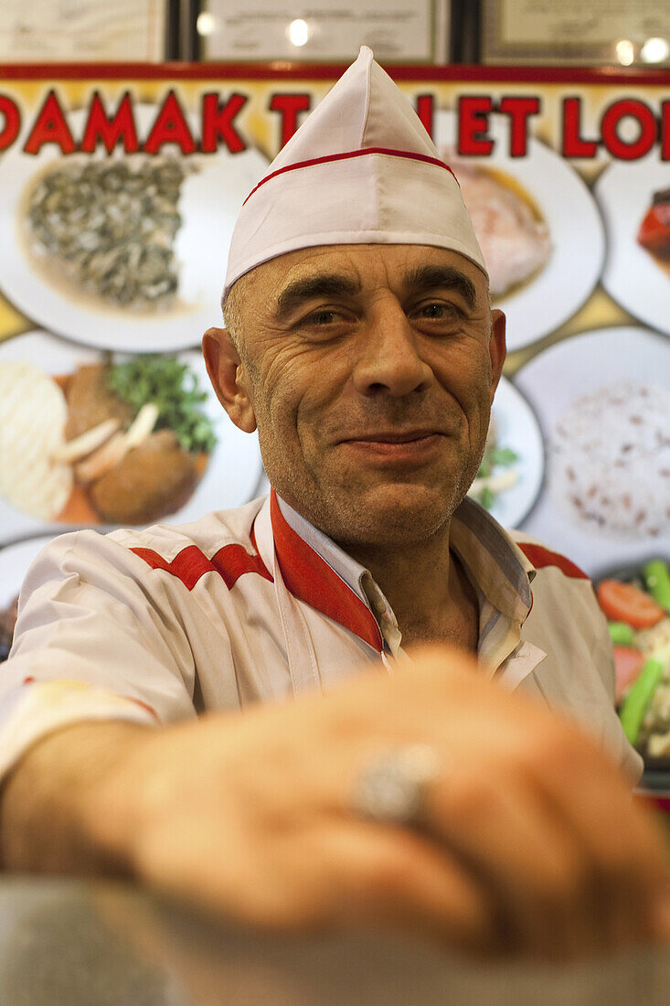 cook with hat behind the counter of a small restaurant, Istanbul, Turkey