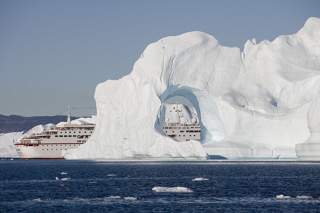 Cruise ship MS Deutschland and iceberg with hole from Ilulissat Kangerlua Icefjord, Ilulissat (Jakobshavn), Disko Bay, Kitaa, Greenland