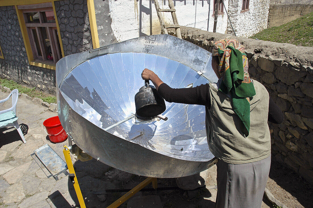 Nepalese woman cooking with a solar cooker  Annapurna Circuit,  Nepal