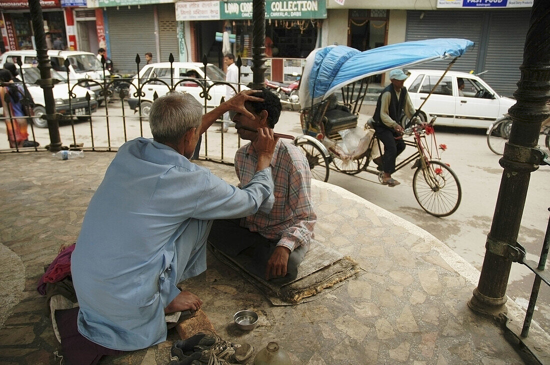 A man getting a shave from a street barber  Thamel,  Kathmandu,  Nepal