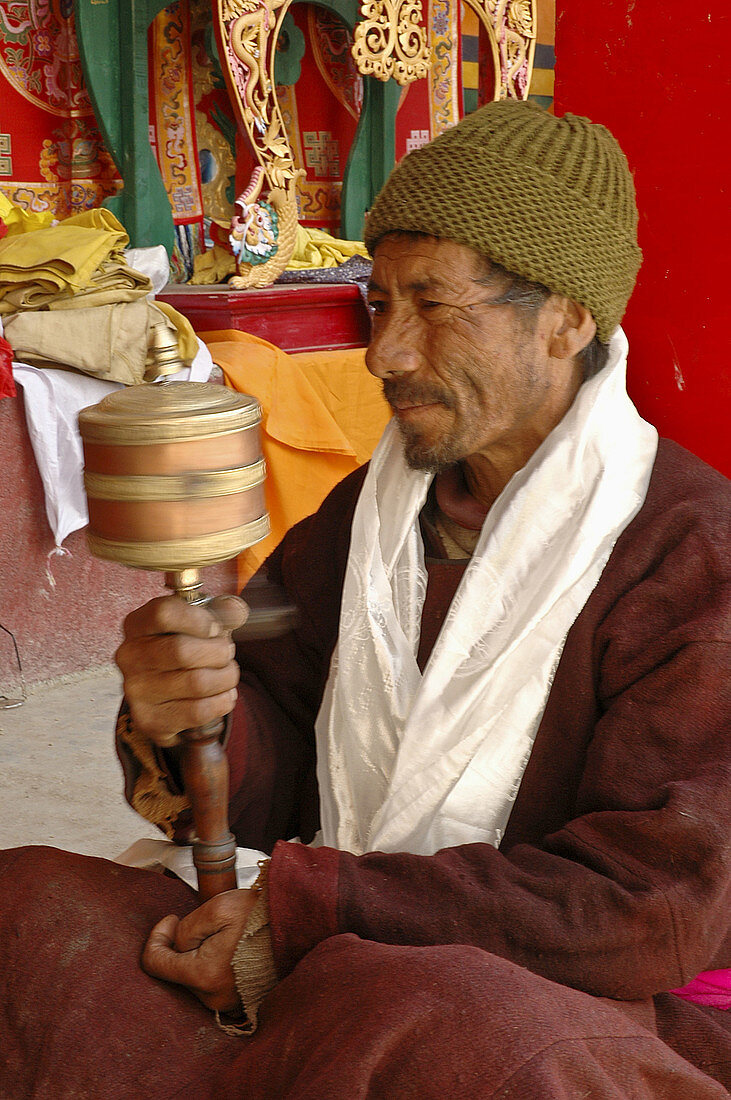 A man using a hand prayer wheel at the festival of Lama Yuru monastery Ladakh,  India