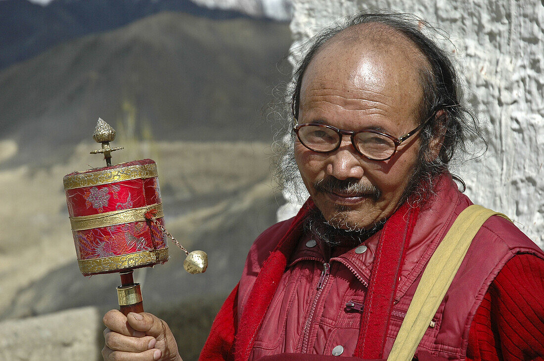 Old tibetan monk spinning a hand held prayer wheel Lama Yuru,  Ladakh,  India