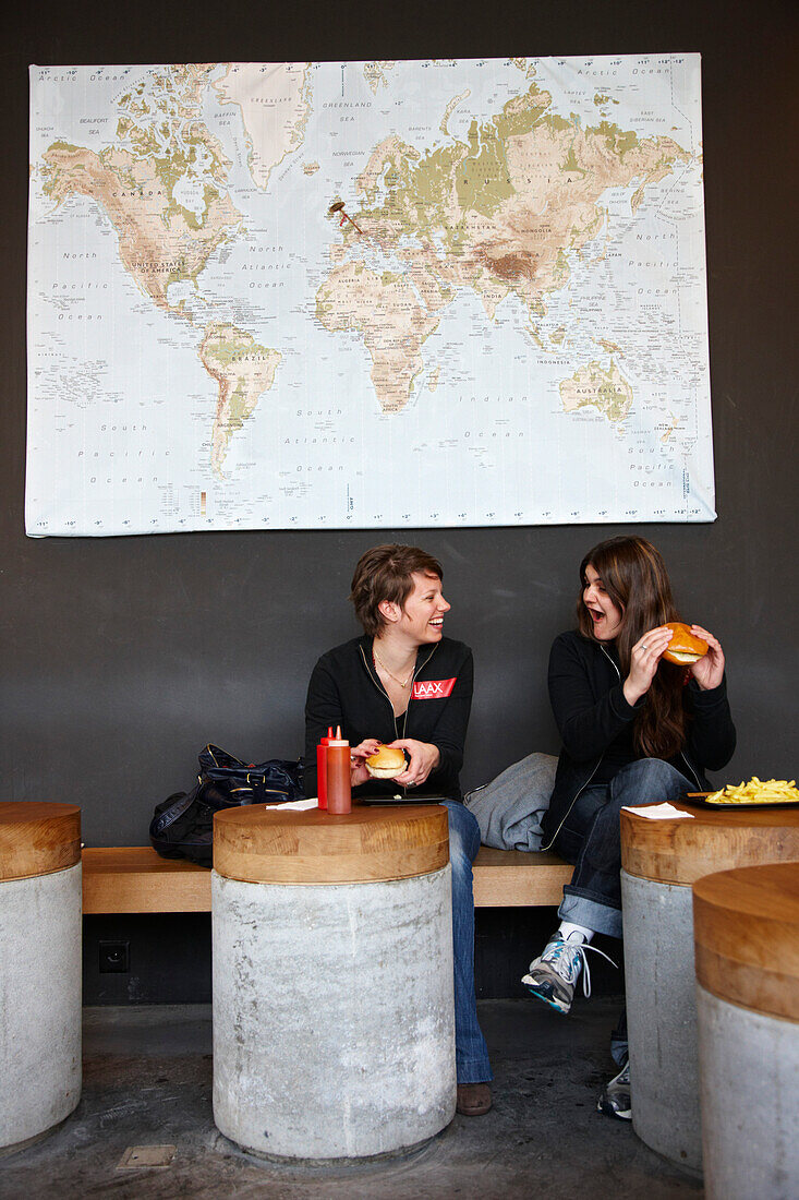 Zwei junge Frauen essen Hamburger im Burgers, Rocksresort, Laax, Kanton Graubünden, Schweiz