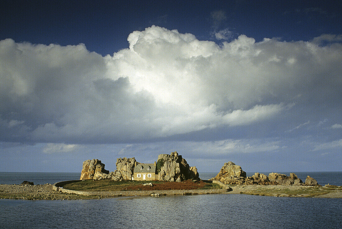 Einsames Haus zwischen Felsen unter Wolkenhimmel, Pointe du Château, Bretagne, Frankreich, Europa