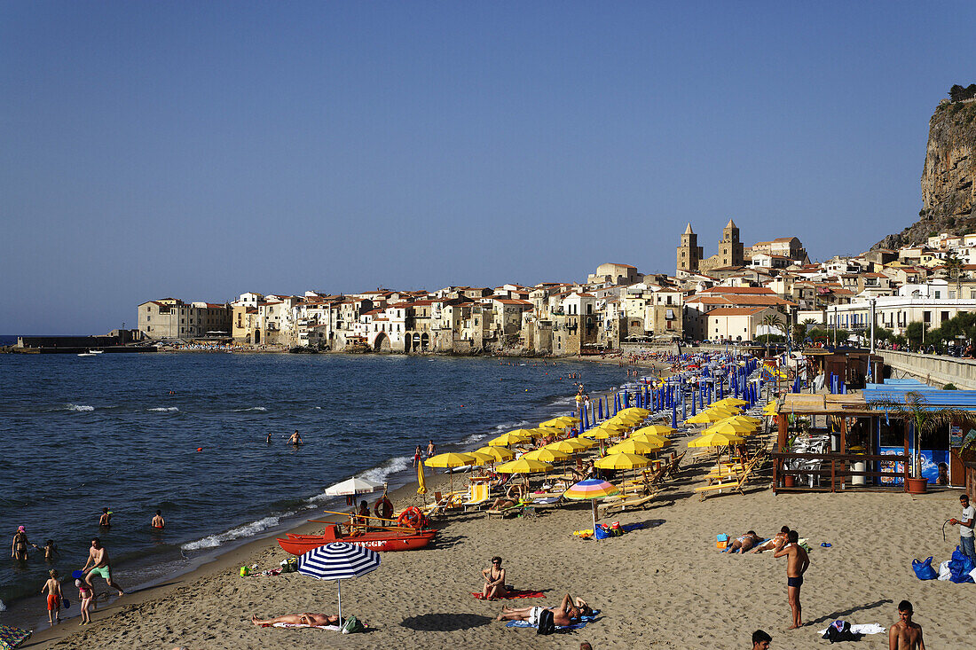 View along beach to Cefalu with Duomo in background, Sicily, Italy