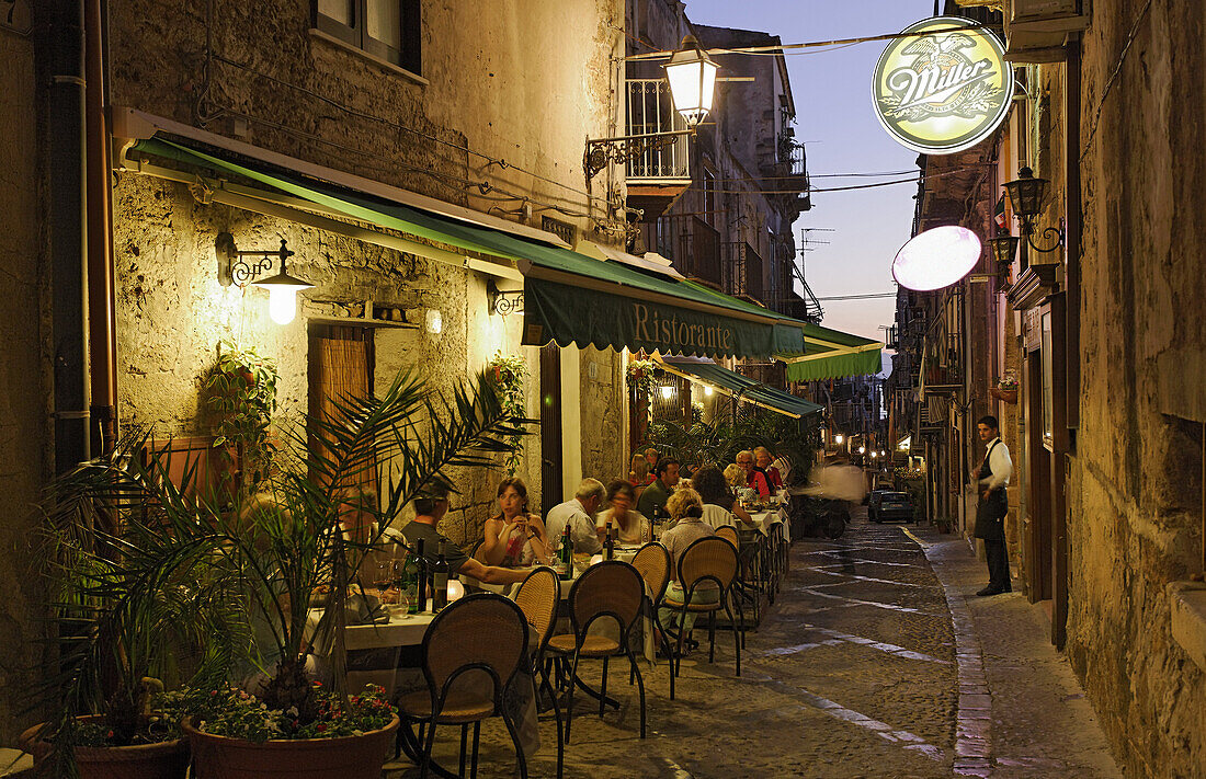 Gäste sitzen vor einem Restaurant am Abend, Cefalu, Sizilien, Italien