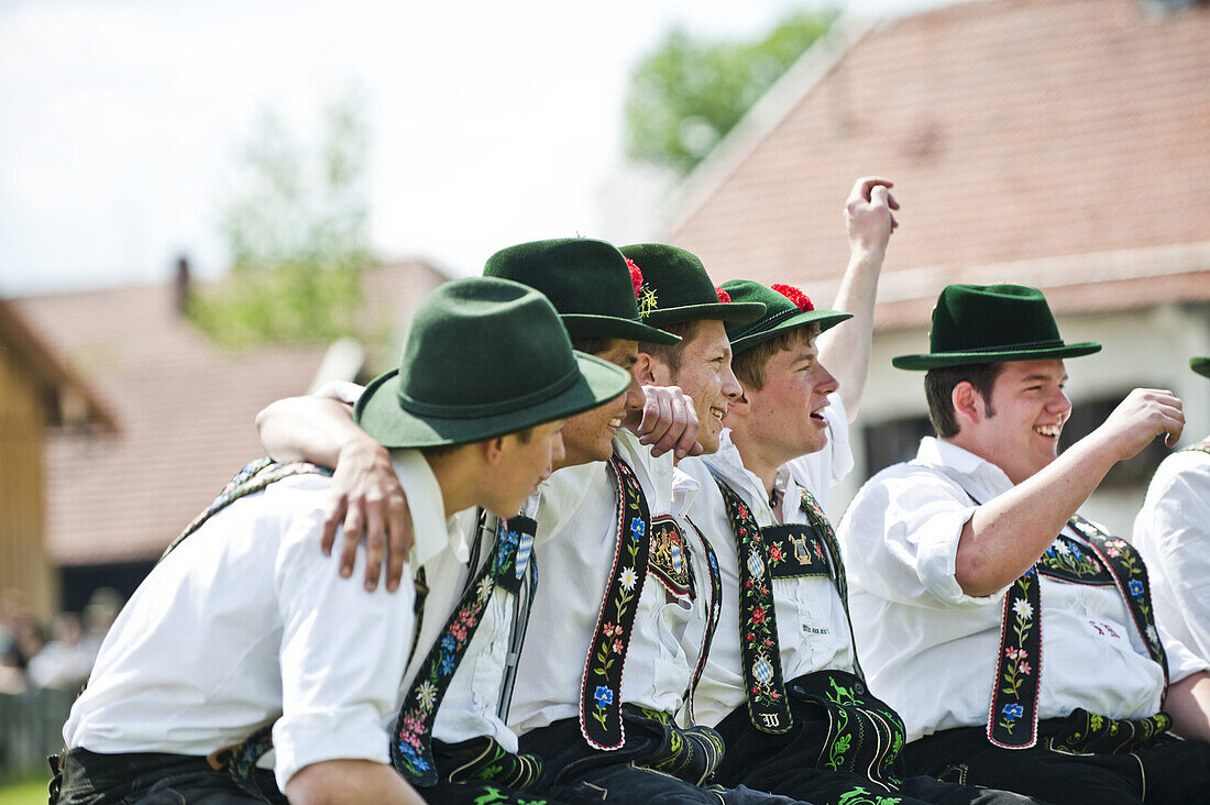 Junge Männer in Tracht sitzen nebeneinander, Mailaufen, Antdorf, Oberbayern, Deutschland