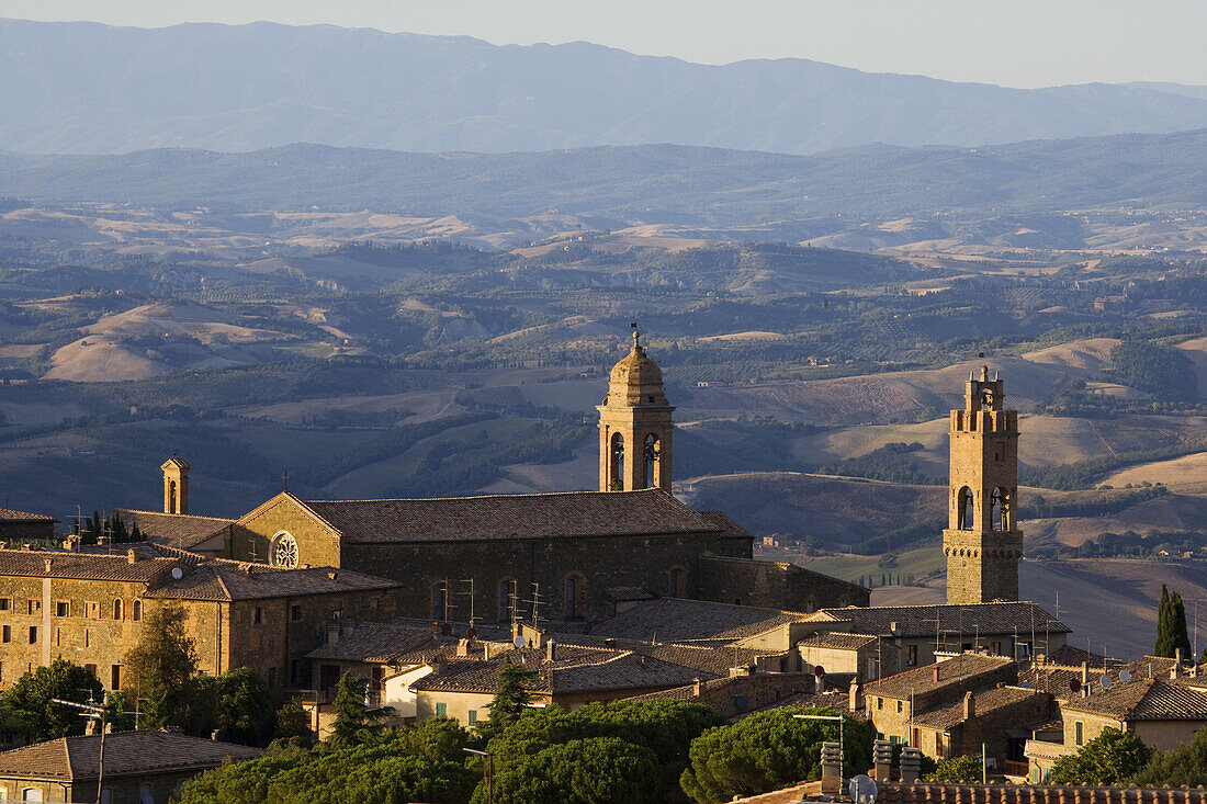 Blick über die Dächer von Montalcino mit dem Turm des Palazzo Comunale (r.) und die Hügellandschaft der Toskana, Italien