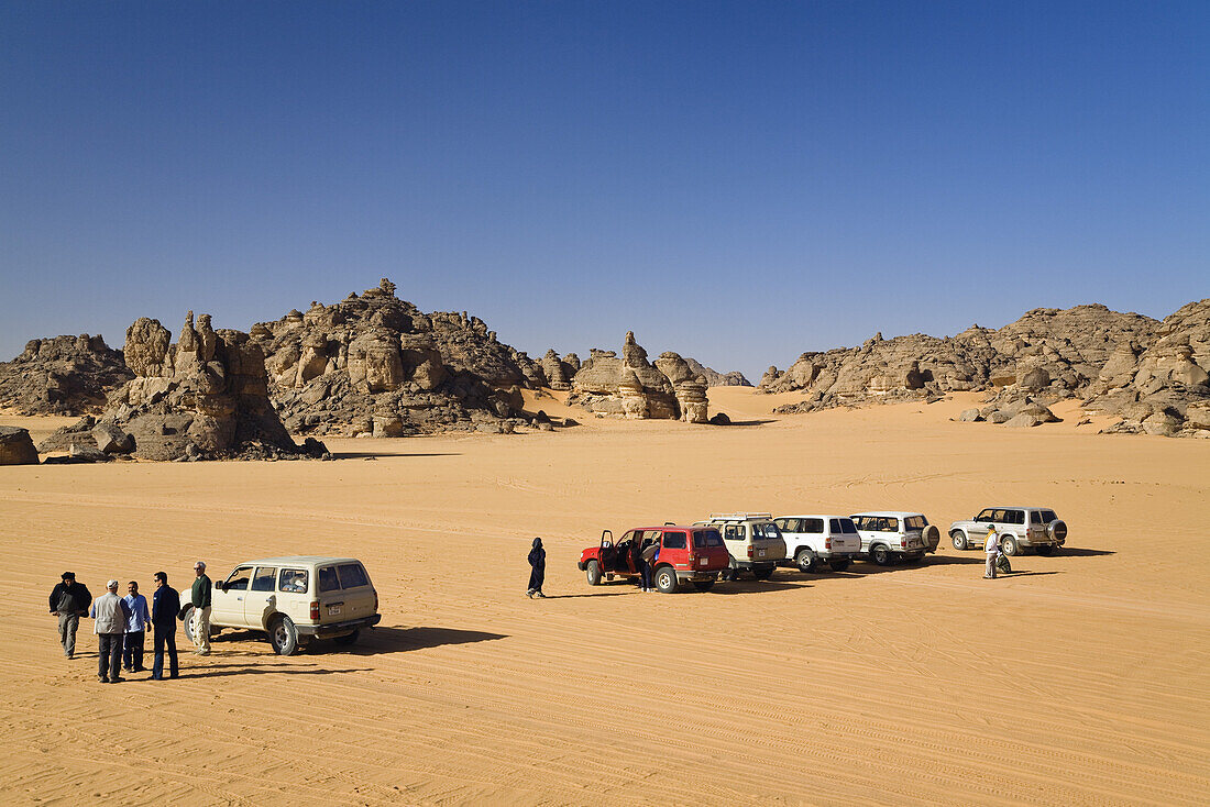 Jeeps and tourists in stony desert, Akakus mountains, Libya, Sahara, North Africa