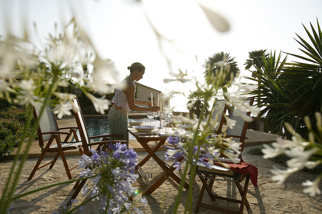 Woman decorating a garden table, in front of a swimming pool, Mallorca, Balearic Islands, Spain