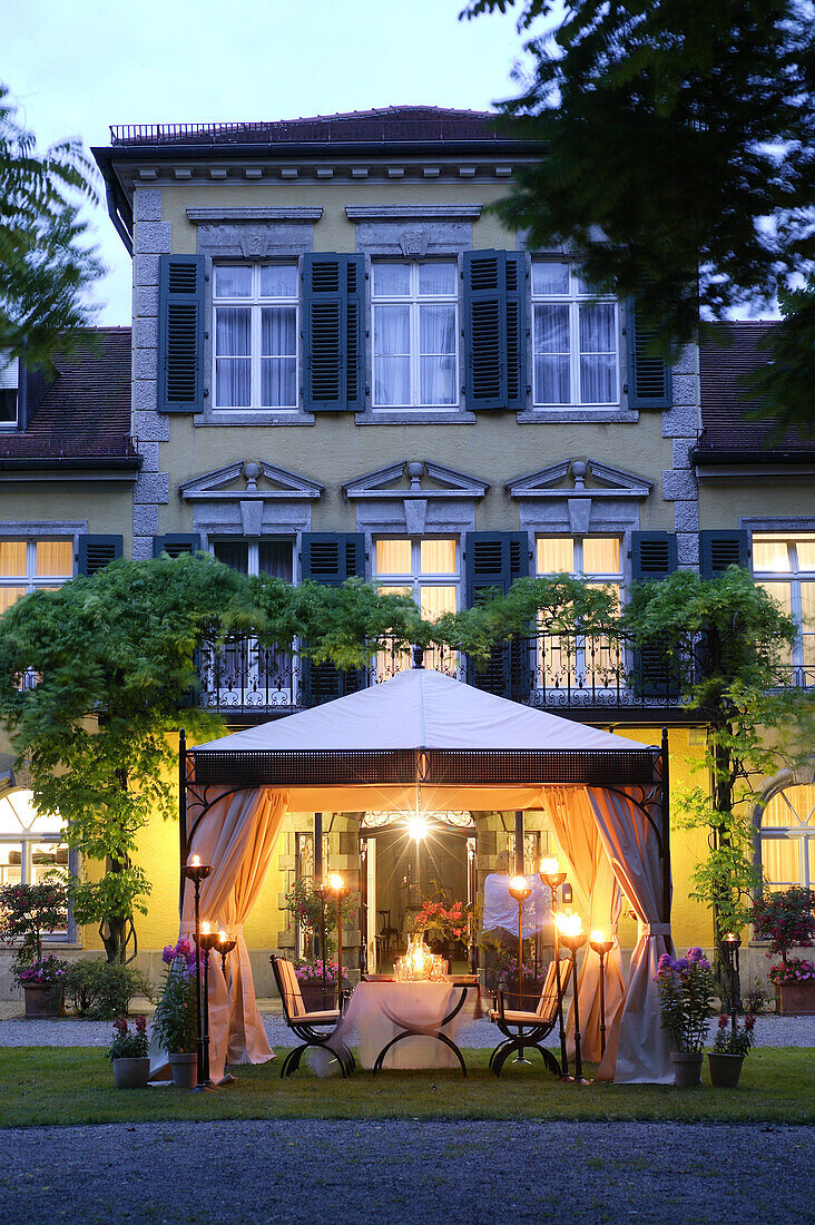Elegant setting with wrought iron garden furniture under garden pavillon, Munich, Bavaria, Germany