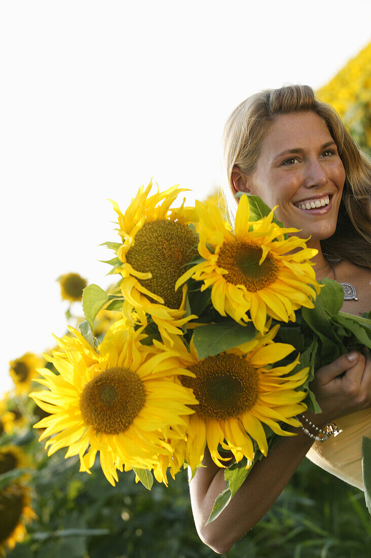 Junge Frau mit Sonnenblumenstrauss, Bayern, Deutschland