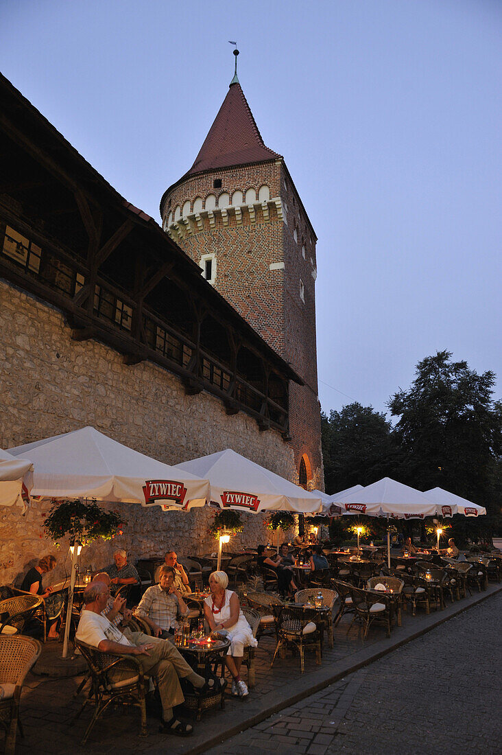 Menschen sitzen abends vor der alten Stadtmauer in einem Strassencafe, Krakau, Polen, Europa