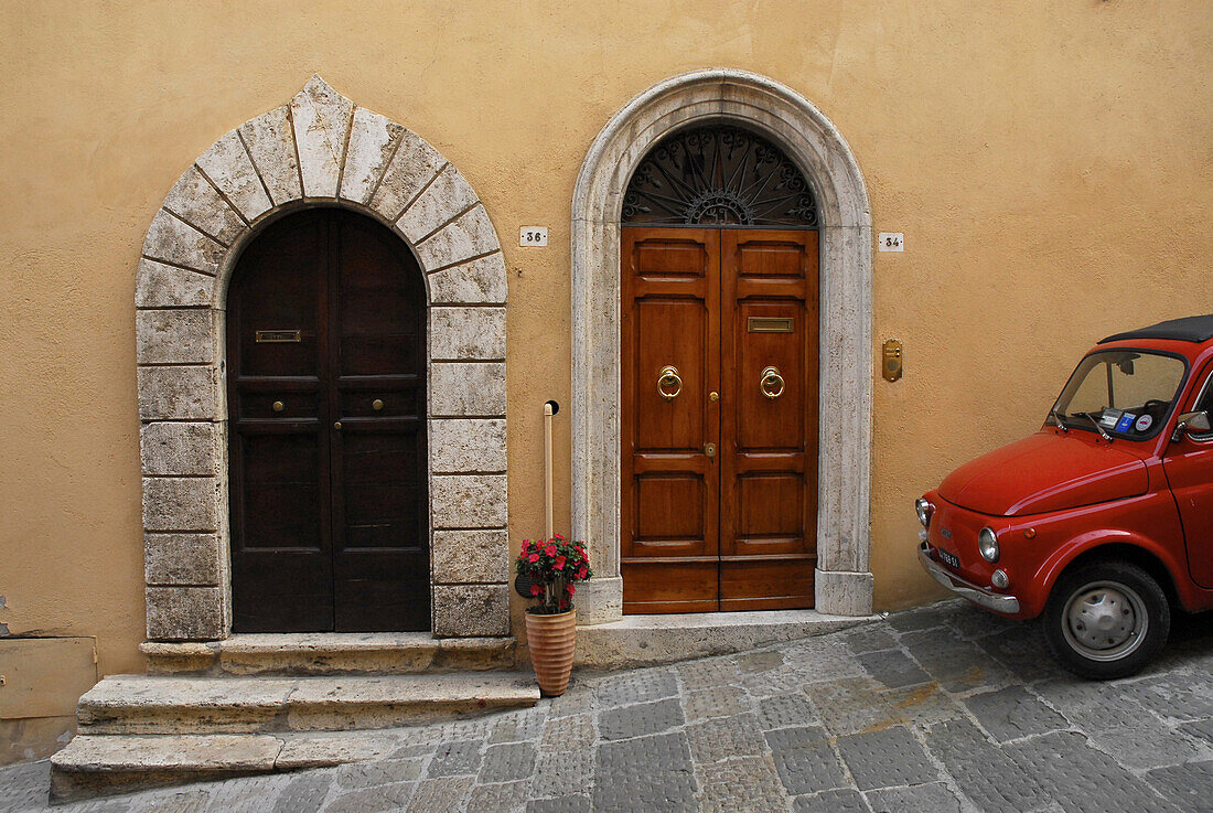 Red Fiat 500 on a steep alley in front of house with doors at Montepulciano, Tuscany, Italy, Europe