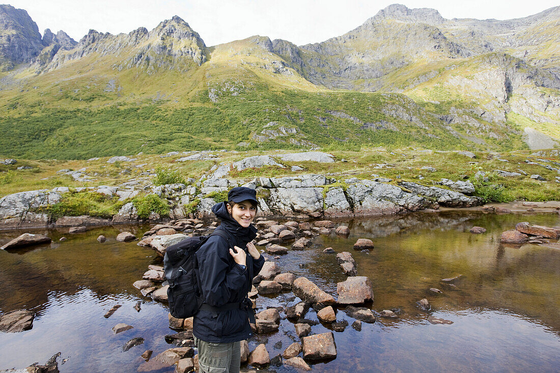 Junge Frau am Ufer eines Sees in den Bergen, Lofoten, Norwegen, Skandinavien, Europa