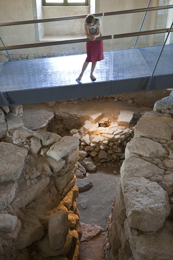 Young woman looking at the excavation objects at Palazzo Zapata, Nuraghe Su Nuraxi, biggest excavated Nuraghic culture complex on Sardinia, ruins of 200 cabins, Barumini, Sardinia, Italy, Europe