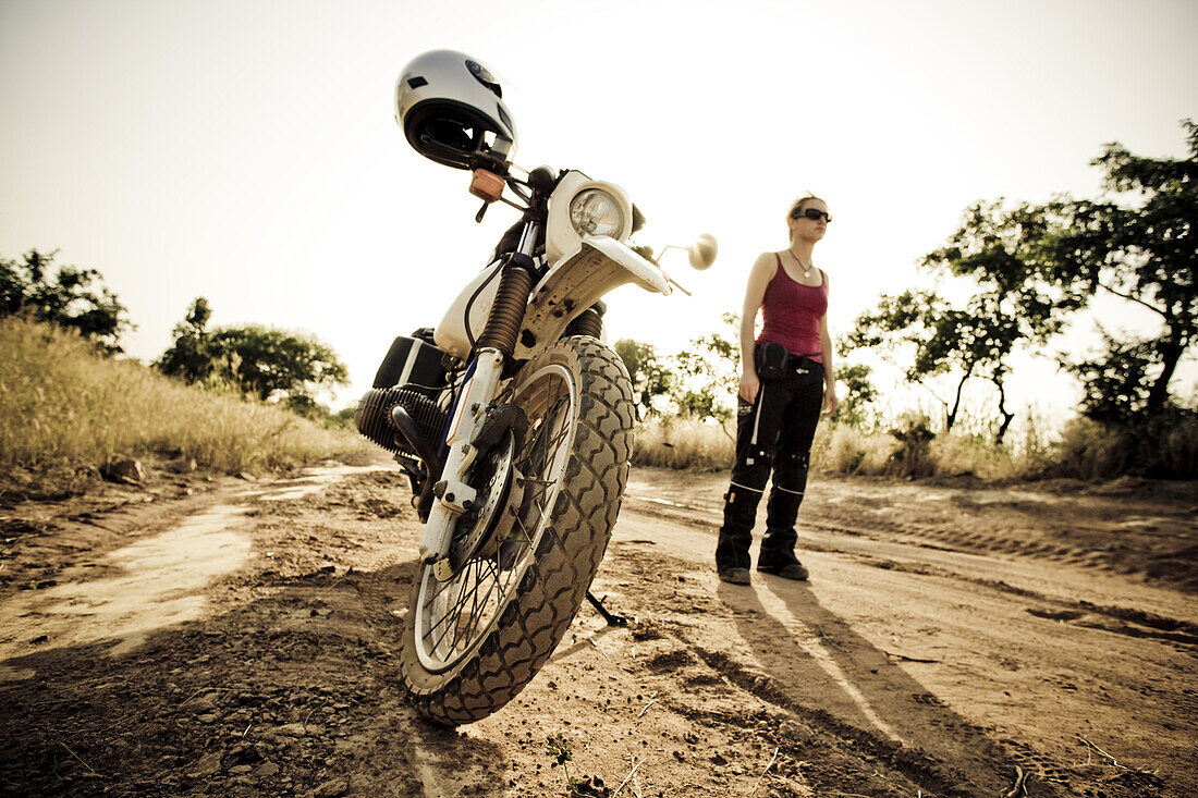 Young woman and motorcycle on dirt road, Atakora, Benin