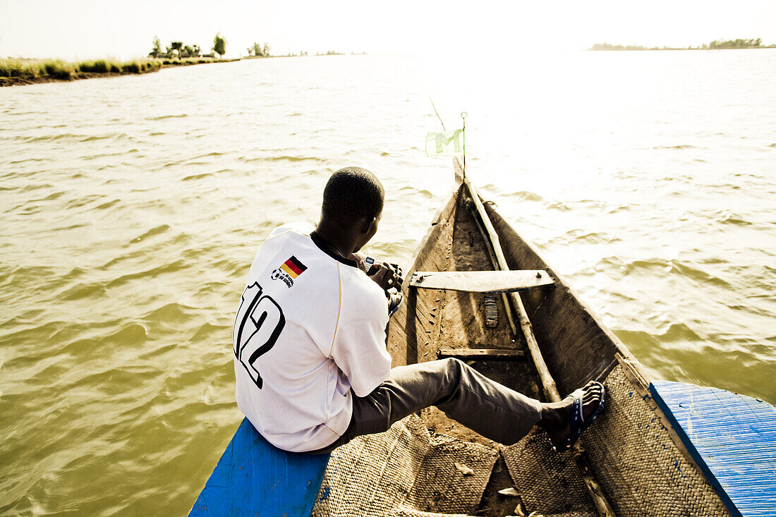 African man with german football shirt on a boat on the river Niger, Mopti, Mali, Africa