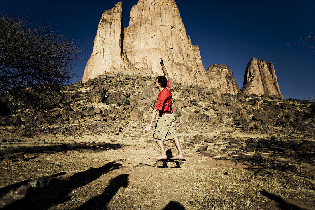 Junger Mann balanciert auf Slackline, im Hintergrund die Hand der Fatima, Hombori, Mali, Afrika