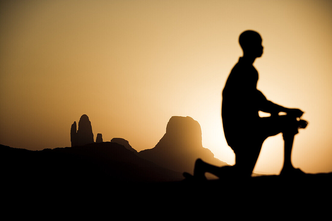 Kneeling boy in front of rock formation at sunset, Hombori, Mali, Africa