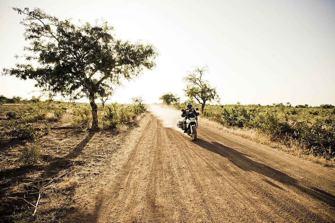 Man on motorcycle riding on a dirt road, Mali, Africa