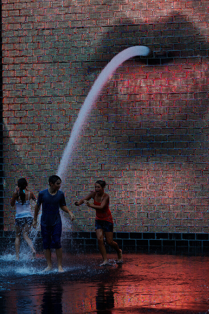 Teenagers playing in The Crowne Fountain by Jaume Plensa, Millenium Park, Chicago, Illinois, USA