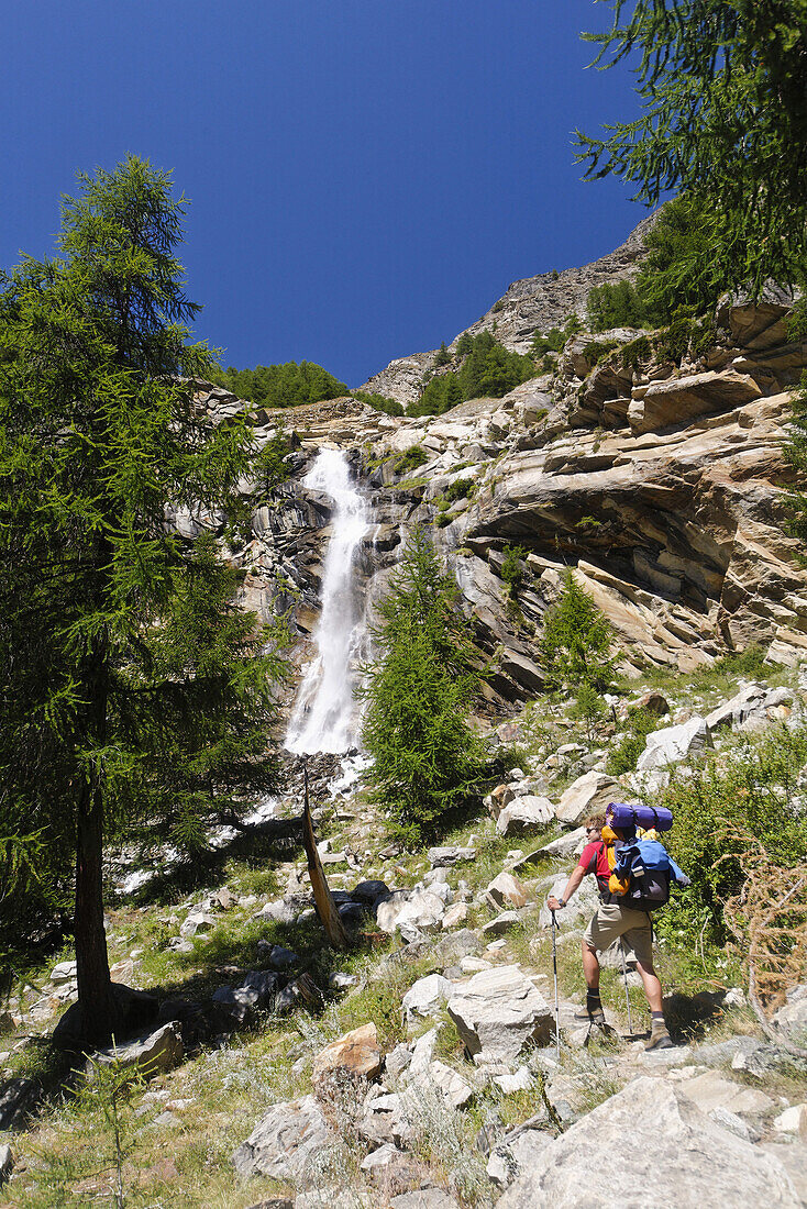 Hiker ascendiong, Cascata Lauson, Valnontey valley, Gran Paradiso National Park, Aosta Valley, Italy