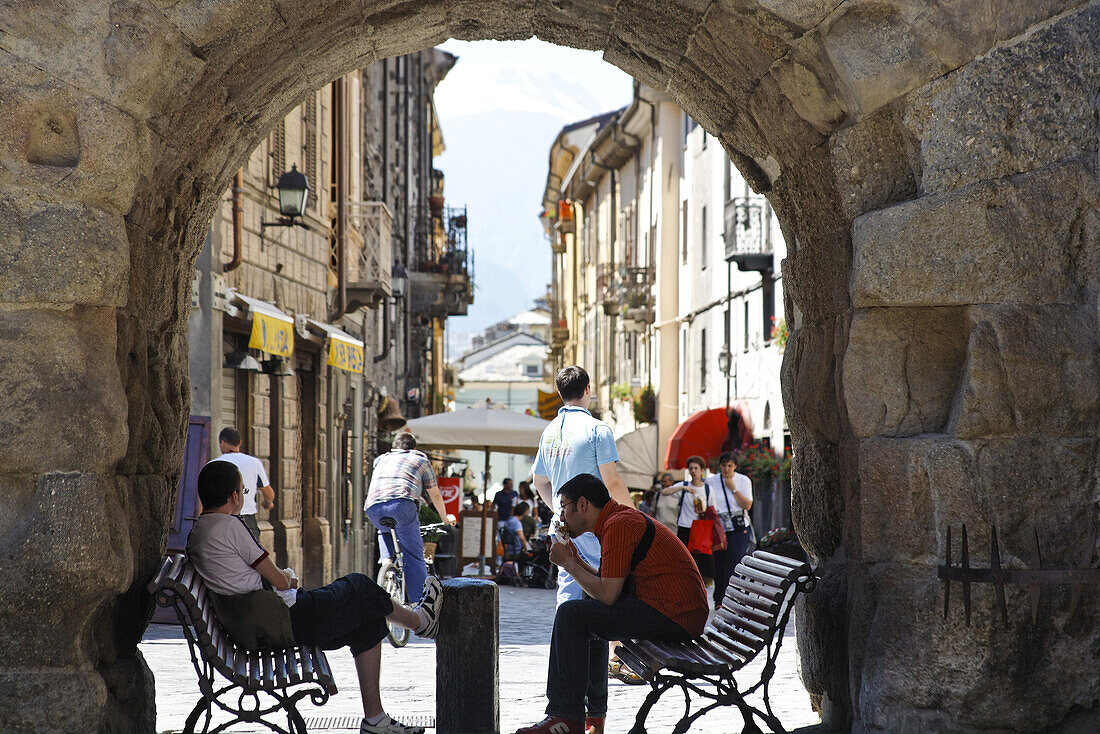 Two persons sitting in an archway, old town, Aosta, Aosta Valley, Italy