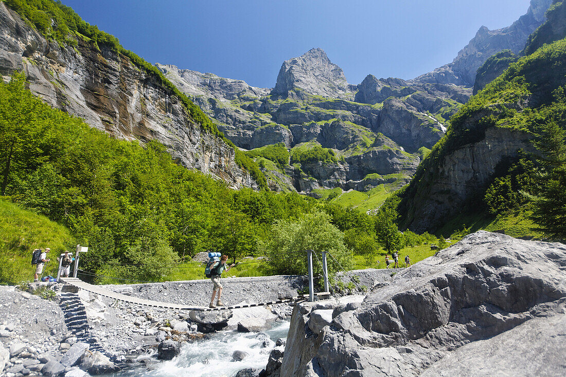 Hikers crossing a bridge, Cirque Fer à Cheval, Haut Giffre, Haute Savoie, France