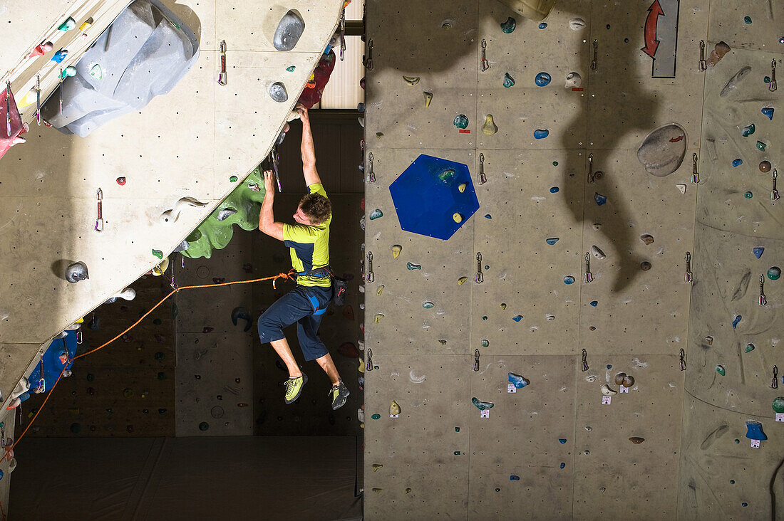 Mann klettert an einem Überhang in einer Kletterhalle, Linz, Öberösterreich, Österreich