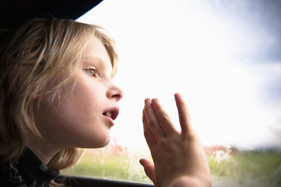Junge blickt aus einem Autofenster, Österreich