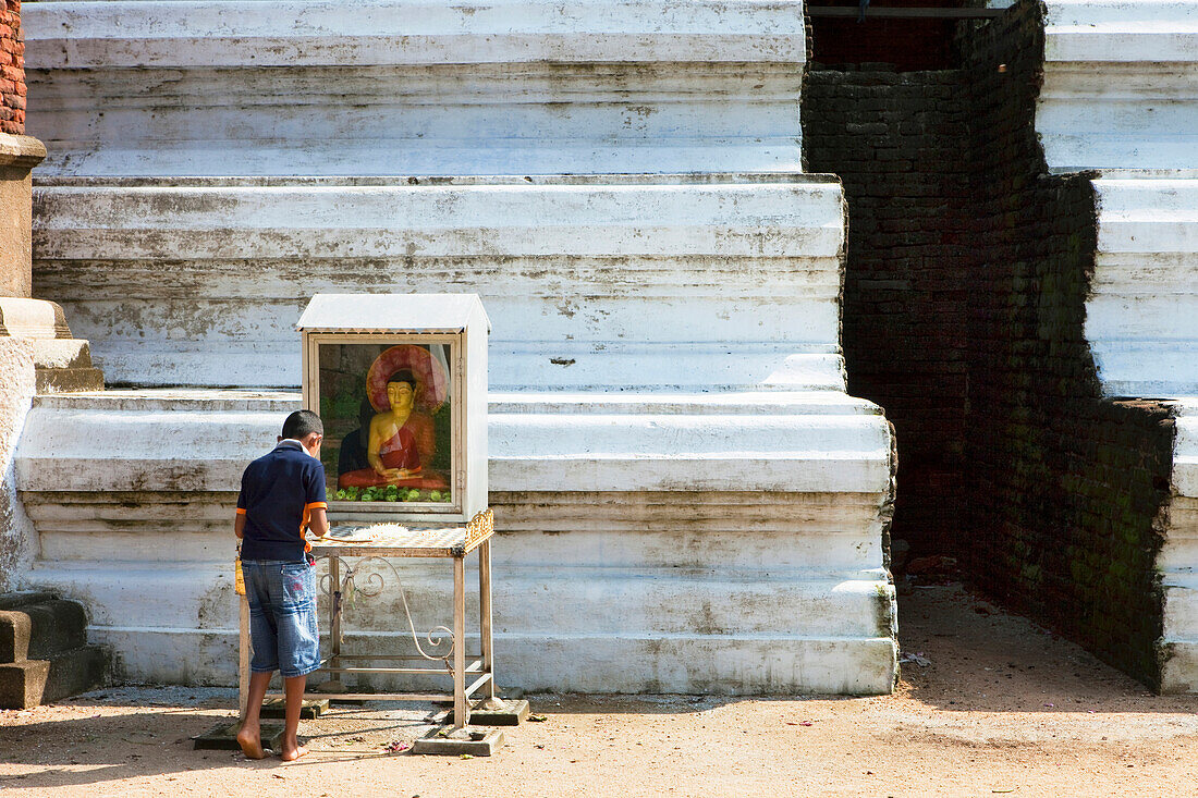 Singhalesischer Junge betet vor einem Buddha in der Mirisawetiya Dagoba, Sacred City, Anuradhapura, Sri Lanka, Asien