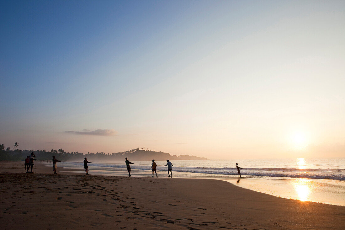 Fishermen in the morning at Talalla beach pulling in their fishing net, Talalla, Matara, South coast, Sri Lanka, Asia