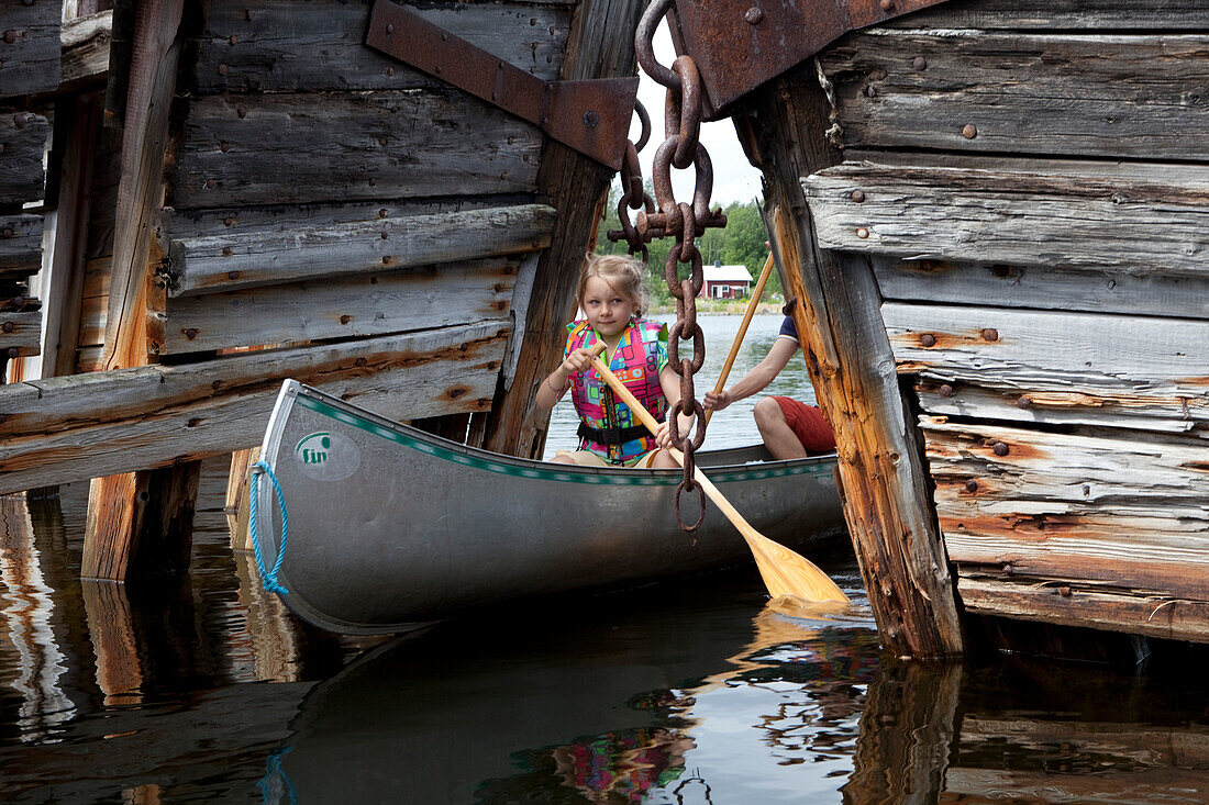 Ein Mädchen in einem Kanu zwischen Schiffswrack,s Insel Norrbyskär, Västerbotten, Schweden, Europa