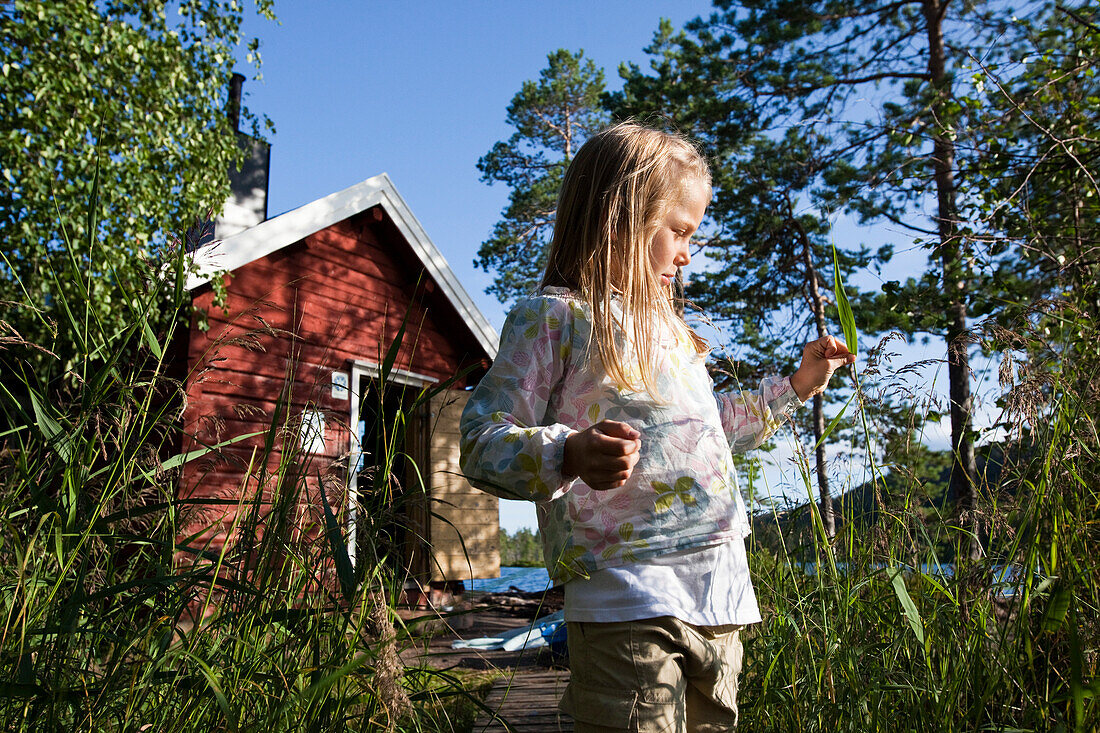 Girl in front of small cottage at the lake Tärnättvatten, national park Skuleskogen, Höga Kusten, Vaesternorrland, Sweden, Europe