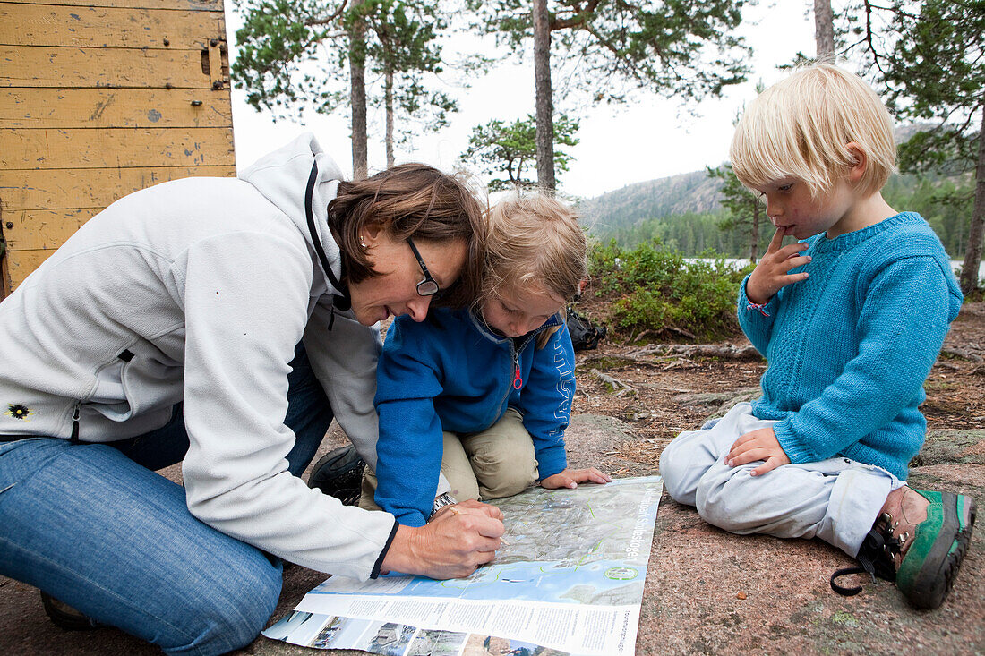 Frau und zwei Mädchen betrachten einer Wanderkarte im Nationalpark Skuleskogen, Höga Kusten, Vaesternorrland, Schweden, Europa