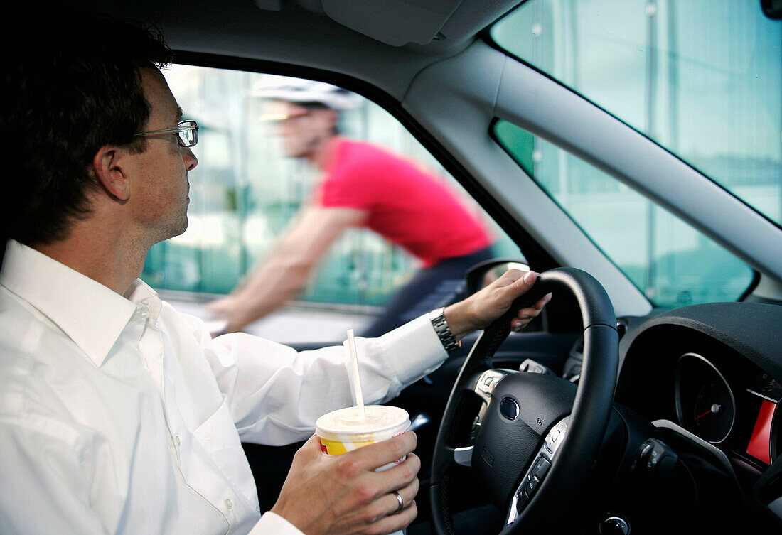 Businessman in a car, cyclist passing