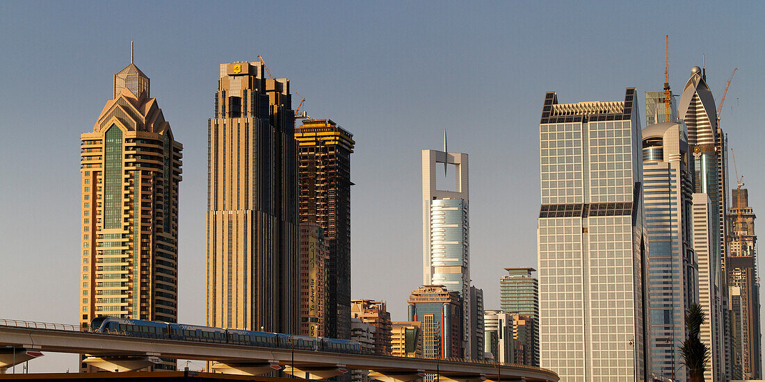 Neue Metro vor Skyline des Finanzzentrums von Dubai an der Zeihet Road